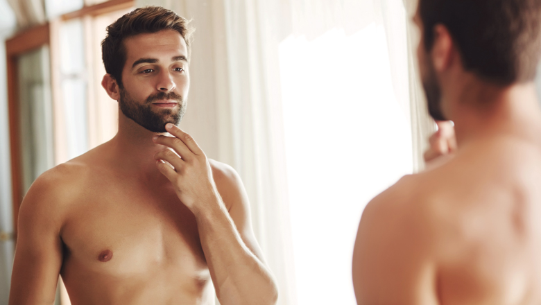 confident shirtless man looking in mirror